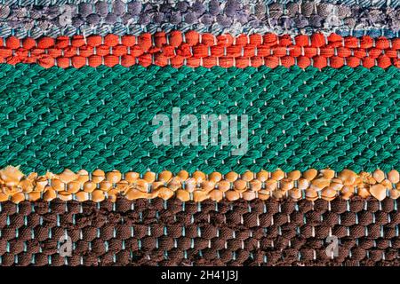 Close up of a colorful handmade motley striped rug or carpet of different colors - red, green, yellow and brown. Stock Photo