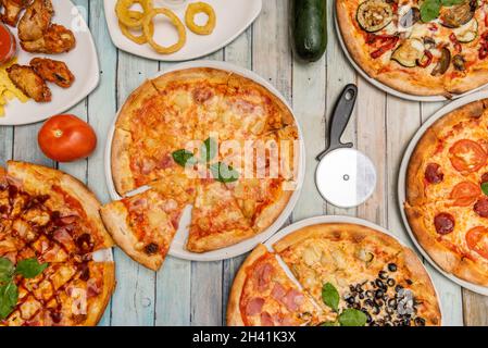 Top view image of Hawaiian pizzas, pepperoni, barbecue pizza, onion rings, four seasons, and a slice of barbecue wings with fries Stock Photo