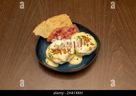Eggs Benedict, from an English muffin, toast or other types of bread, usually topped with cooked ham, bacon or pastrami, poached eggs, and the very po Stock Photo