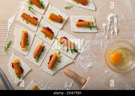Cooking process sausages with cheese in wrapped dough - top view Stock Photo