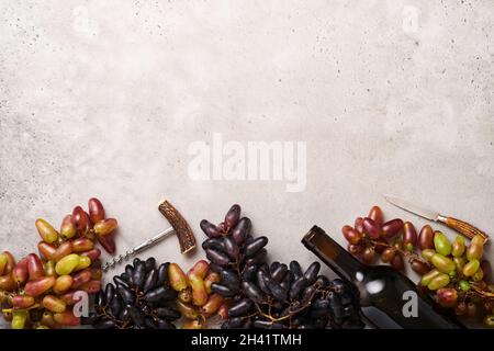 Two Wine bottles with grapes and wineglasses on old gray concrete table background with copy space. Red wine with a vine branch. Wine composition on r Stock Photo
