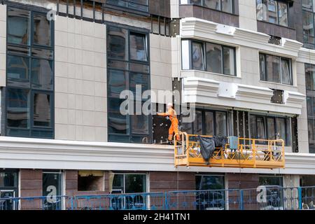 KIE, UKRAINE - Oct 03, 2021: A worker assembles a ventilated facade on a residential building under construction in Kyiv Stock Photo