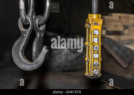 Remote control old control panel lifting industrial mechanism iron hook in the workshop of the industrial plant. Stock Photo