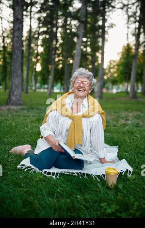 Dranny in glasses reading a book on the grass Stock Photo