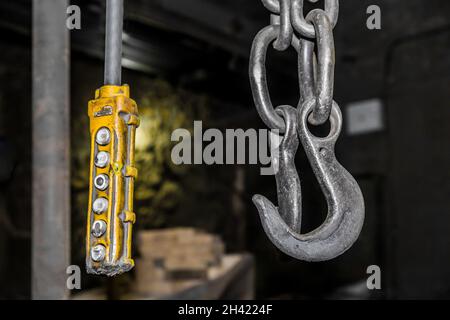 Remote control old control panel lifting industrial mechanism iron hook in the workshop of the industrial plant. Stock Photo