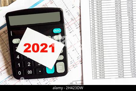 On the display of the calculator 2021. There are papers with numbers on the table Stock Photo