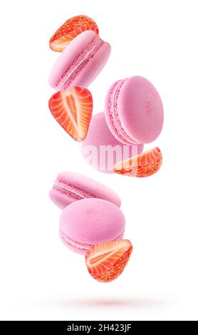 Isolated strawberry macarons. Falling pink macaroons and pieces of fresh strawberries isolated on white background Stock Photo