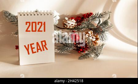 On a white background lies a fir branch with New Year's toys and a calendar with the text 2021 year Stock Photo