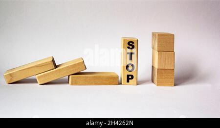 Concept of hand stop falling wooden blocks on a white background. On the block the word STOP. Stock Photo