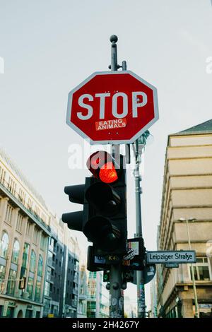 October, 2021 - Berlin Germany. Traffic red sign Stop and eat animals sticker on street. Call for veganism, humanity. Protest of eating meat. Stock Photo