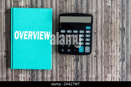 OVERVIEW word printed in white ink on a green notebook, next to a calculator on a wooden table .Trends business concept. Stock Photo