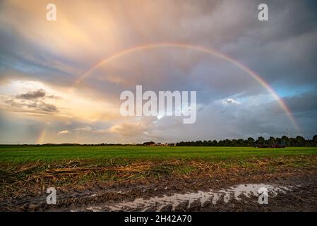 Bright rainbow over the Dutch countryside after a thunderstorm that left a good amount of rain behind Stock Photo