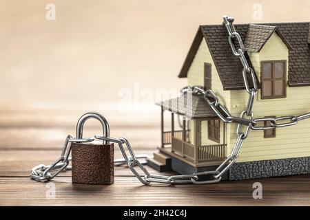 House tied with a chain and a closed lock. The concept of a ban on the sale of real estate, house arrest. Stock Photo