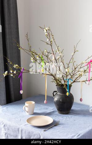 Blooming cherry branches decorated with colorful ribbons with easter eggs, Happy Easter, table setting Stock Photo