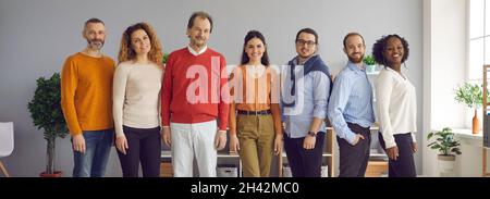 Group portrait of happy diverse people in comfortable casual wear standing in office Stock Photo