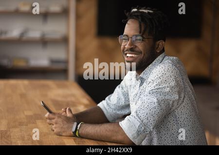 Happy dreamy young african man using cellphone. Stock Photo