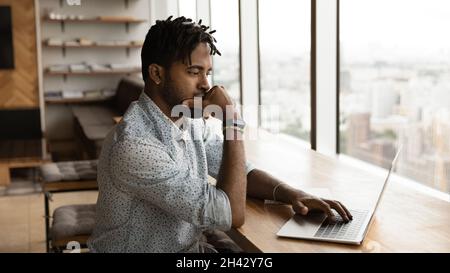 Thoughtful young mixed race businessman working on project. Stock Photo