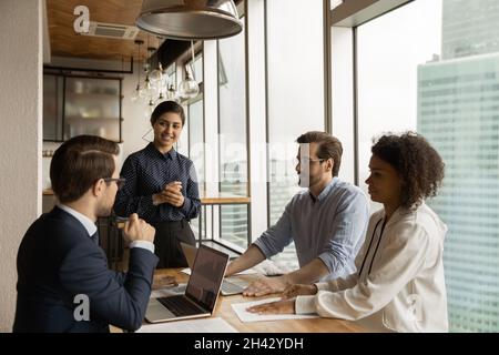 Happy indian team leader holding negotiations meeting with diverse colleagues. Stock Photo