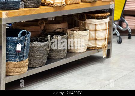 Laundry basket. Woven straw basket, container and boxes on a shelf in store. Bamboo weaving basket and brown Linen on shelf of rack background. Househ Stock Photo