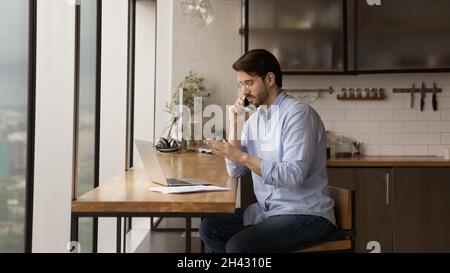 Concentrated young businessman multitasking at home office. Stock Photo