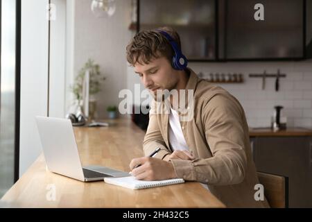 Happy young handsome man e-learning, writing notes. Stock Photo