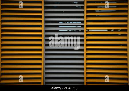 window blinds made of wood in orange and gray and a reflection in the window on the glass behind the wooden blinds Stock Photo