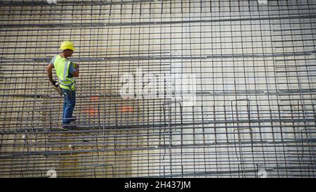 Construction workers assembling steel reinforcement bars on the site of a new building. Milan, Italy - October 2021 Stock Photo