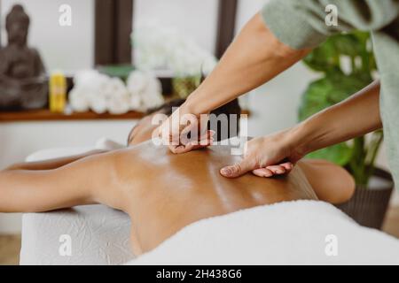 African American woman having back massage in modern spa salon. Stock Photo