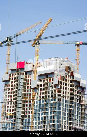 Large residential tower under construction with three yellow large cranes on top in The Hague in the Netherlands Stock Photo