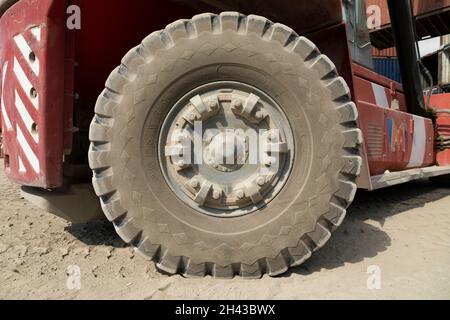 Labuan Bajo, Indonesia - Aug 25, 2019: The huge dirty gray rubber wheel of a crane in Labuan Bajo container and port area Stock Photo