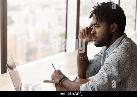 Thoughtful young brazilian man working on computer. Stock Photo