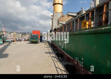 Labuan Bajo, Indonesia - Aug 25, 2019: A truck, loaded with a container, next to a cargo ship in the port of Labuan Bajo Stock Photo