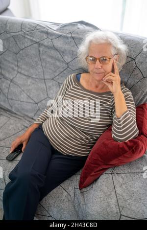 Portrait of a mature woman sitting on her sofa at home Stock Photo