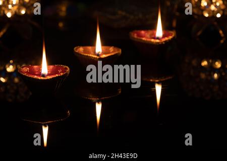 Glowing glittering Clay Diya Deep Dia lamps arranged or placed in a sequence pattern on a reflective base for Hindu festival Laxmi pooja Diwali, Stock Photo