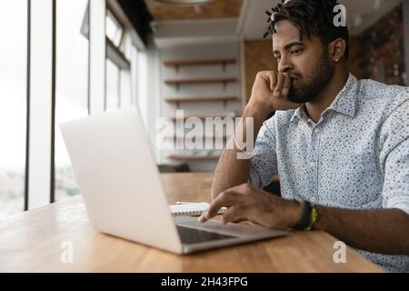Pensive millennial african american man working on computer. Stock Photo