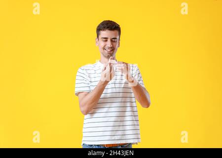 Young man applying plaster onto his finger on yellow background Stock Photo