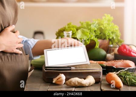 Pregnant woman using digital recipe book for cooking in kitchen, closeup Stock Photo