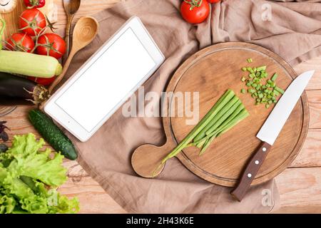 Tablet computer and fresh vegetables on table in kitchen Stock Photo