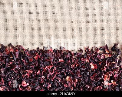 Straw mat background with dry hibiscus tea, closeup. Flat lay, top view. Stock Photo