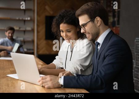 Happy young mixed race business people working on computer. Stock Photo