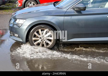 Kidderminister, England - October 2021: Water splashing as a car drives through a large puddle of water after heavy rain from a storm Stock Photo