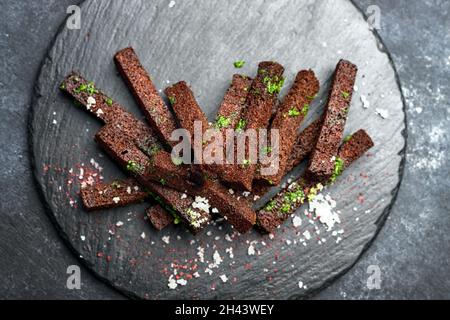 Black bread beer croutons with garlic salt and herbs on a black background Stock Photo