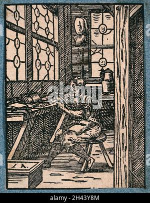 A man is sitting on a stool at a bench working. Woodcut. Stock Photo