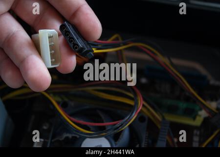 Man hand holding a molex male and female ends of sockets and connecting them into one piece to make computer work again. Stock Photo