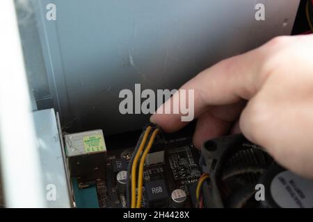 Man hand putting electrical connections of a computer in right sockets to run computer properly. Power cable connections. Stock Photo