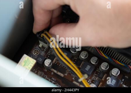 Man hand putting electrical connections of a computer in right sockets to run computer properly. Power cable connections. Stock Photo