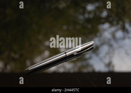 A shiny silver pen on a black surface. Stock Photo