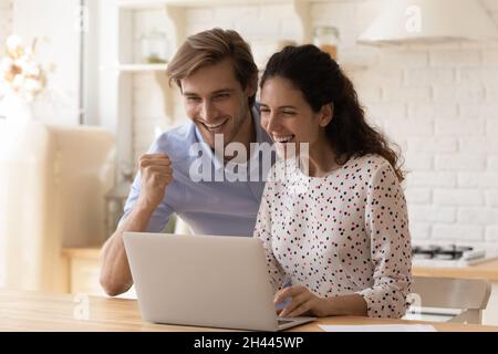 Happy couple read e-mail on laptop celebrate bank loan approval Stock Photo