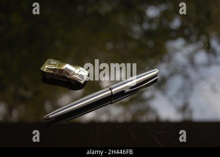 A shiny silver pen on a black surface. Stock Photo