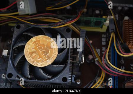 A bitcoin on a dirty and old computer's cpu cooling fan. Stock Photo